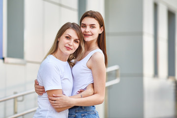 a woman and her adult daughter in bright clothes are standing and looking at the frame