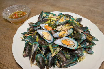 Steaming mussel with white plate on wooden floor