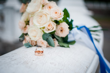 pair of gold wedding rings on the white marble with flowers