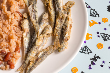 Small fried sardines with red beans rice, a typical Portuguese dish with halloween decoration.