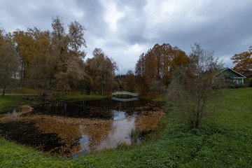 Fototapeta na wymiar White bridge across the pond in the Park. Mikhailovskoye in October. Estate of Pushkin's parents in Mikhailovskoye village, Pskov region, Russia
