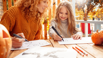 Mother and little daughter drawing spooky ghost for halloween