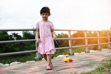 Child having fun playing outside Asian kid girl happy with toys in the park playground - International Children's Day
