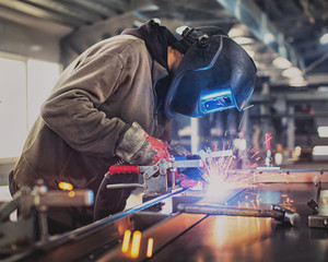 One worker welds steel construction on factory with sparks.