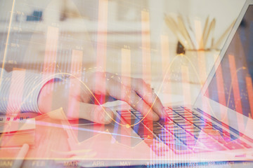 Double exposure of man's hands writing notes with laptop of stock market with forex graph background. Top View. Concept of research and trading.