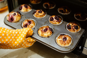 Homemade muffins with cherries in a baking form.