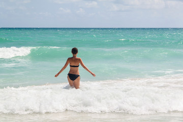 Young woman enjoying warm waves of a beautiful blue sea