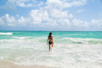 Fototapeta na wymiar Young woman enjoying warm waves of a beautiful blue sea