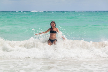Young woman enjoying warm waves of a beautiful blue sea