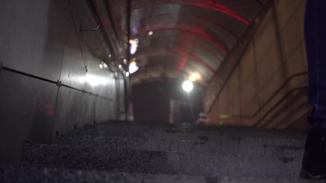woman descends stairs to underpass or subway at night.