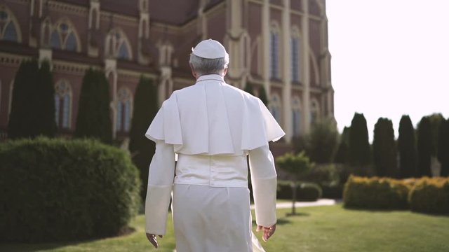 Religion: pope walks through the Vatican garden at sunset. Slow motion