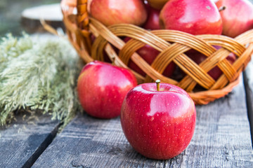 Ripe red apples on a wooden table near a basket with apples. Vitamins and a healthy diet. Vegetarian concept.