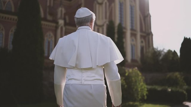 Religion: pope walks through the Vatican garden at sunset. Slow motion