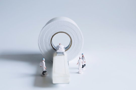 Close up miniature people doctor with CT scan on white background. - Powered by Adobe
