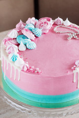Pink cake for the baptism of a girl on a light background with meringues and a cross