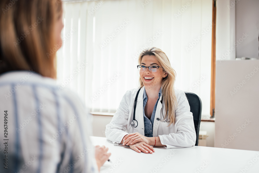 Wall mural portrait of a smiling female doctor with a patient in the office.