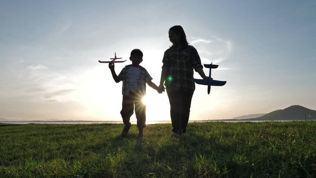 Happy Asian mother and son They walking hand in hand playing airplane Together in the nature that has sunlight in the evening. Family happiness holiday, family relationship. Slow Motion