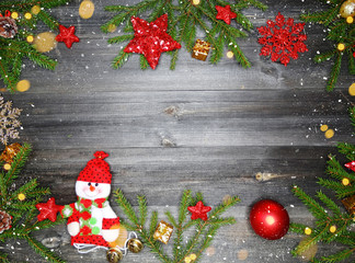 Fototapeta na wymiar christmas fir tree branches with snowman decoration on wooden background