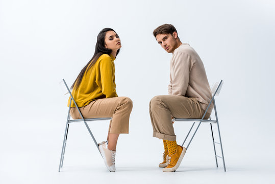 young attractive woman sitting on chair near handsome man on white