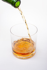 Close-up of an elegant glass for spirits, with a spilled liquor, similar to rum or whiskey, on a white background.