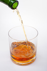 Close-up of an elegant glass for spirits, with a spilled liquor, similar to rum or whiskey, on a white background.