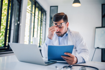 Portrait of overworked doctor at medical office.