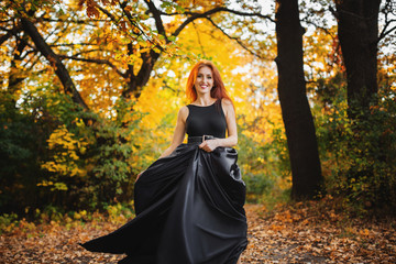 photo of redhead woman in black dress with fluffy skirt. Running towards camera.