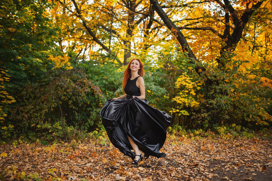 photo of redhead woman in black dress. Running towards camera.