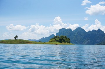 Beautiful view from Ratchaprapa dam in Thailand. Beautiful landscape view with blue water, blue clouds sky and mountains at the background. Tourists in the boat are enjoying the view