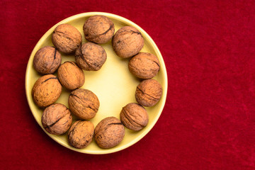 Walnuts in a plate on a red background.