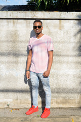 Full body shot of happy young African man with sunglasses smiling outdoors