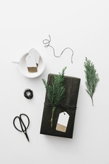 Black gift box with green cypress branch on white table