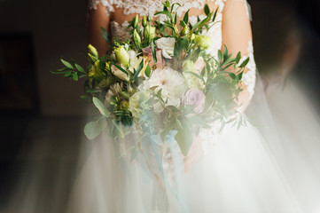 Beautiful bride is holding a wedding colorful bouquet.