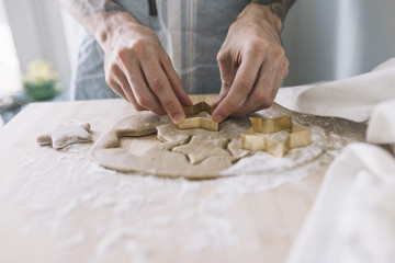 Human hands using cookie cutter on dough
