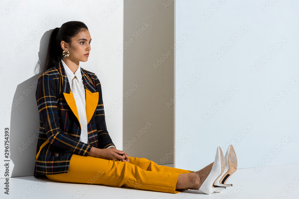 Wall mural young stylish woman sitting on grey and white