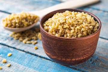 Dry bulgur grain in a bowl. A pile of raw grain Bulgur porridge. Healthy, dietary, vegan, gluten free product. Healthy eating concept. Organic product made from wheat grains.