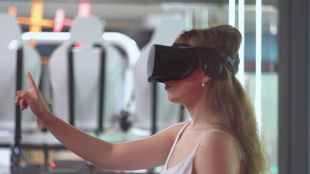 Young girl in virtual reality glasses flips virtual pages horizontally
