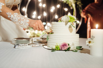 Happy bride and groom cut the cake. Evening ceremony