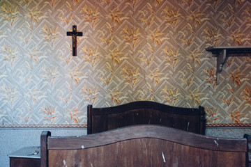 une vieille chambre avec un vieux lit et un crucifix.