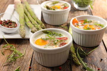 baked egg with asparagus and cream on wood background