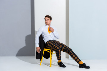 man in checkered trousers sitting on yellow chair on white and grey
