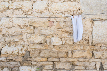 des chaussettes blanches sèchent sur un fil devant un mur de pierre