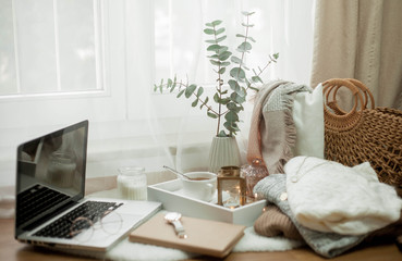 Toned photo. Autumn decor. A laptop, a mug of hot tea, a bun, candles. Cozy. Autumn.