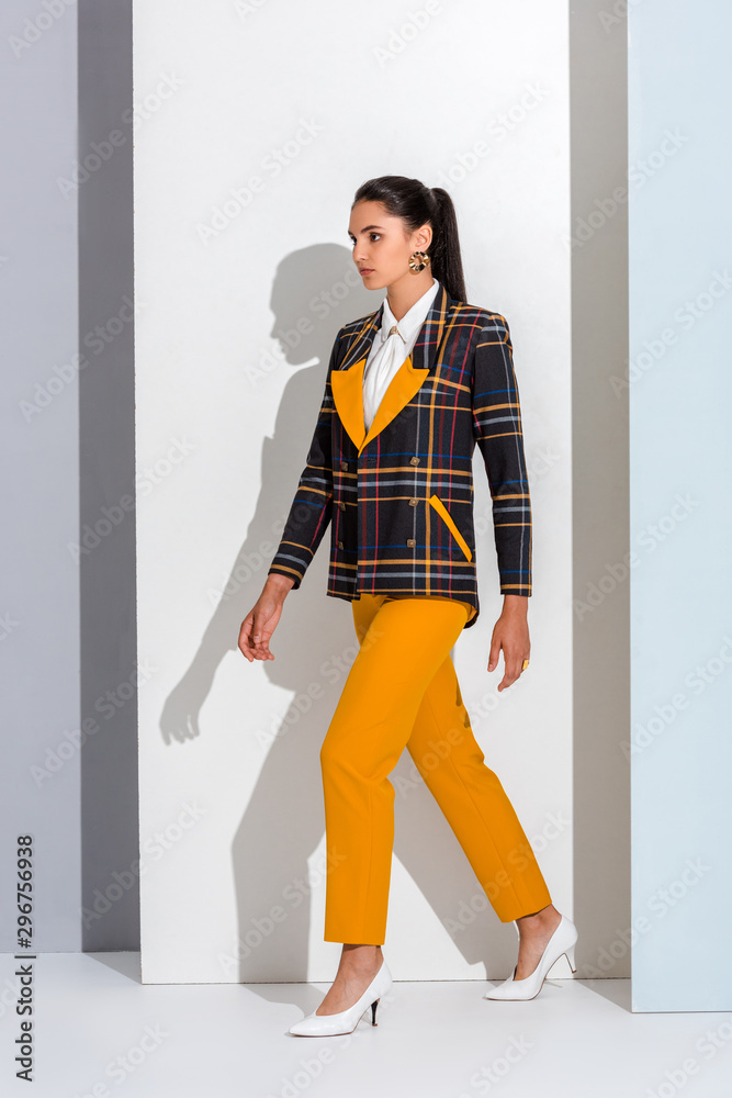 Wall mural stylish girl in checkered formal wear walking on white and grey