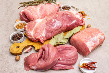 Assorted various pork cuts. Raw meat with spices. Tenderloin, shoulder blade, neck, hind leg steak