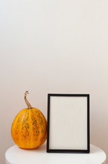 Pumpkin with pfotoframe on white background. Autumn, fall, halloween concept. Flat lay, top view, copy space, mockup.