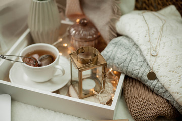 Toned photo. Autumn decor. A laptop, a mug of hot tea, a bun, candles. Cozy. Autumn.