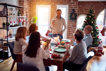 Family and friends dining at home celebrating christmas eve with traditional food and decoration, making a toast for new year best wishes