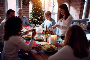 Family and friends dining at home celebrating christmas eve with traditional food and decoration, preparing turkey for dinner