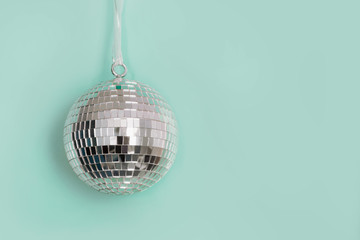 Christmas mirror silver disco ball hanging on neo mint background. Creative Xmas pattern with copy space.